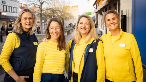 Fyra personer i gula och svarta kläder står ute och ler mot kameran.