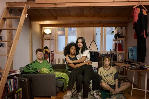 Fyra ungdomar sitter under en loftsäng. En av dem sitter i en soffa, en på golvet och en tredje på en stol. Personen på stolen har den fjärde personen i sitt knä.