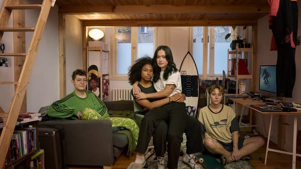 Fyra ungdomar sitter under en loftsäng. En av dem sitter i en soffa, en på golvet och en tredje på en stol. Personen på stolen har den fjärde personen i sitt knä.
