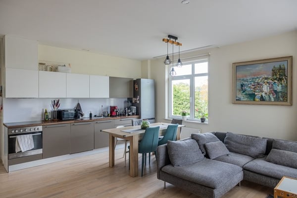 Gaiša, moderna virtuve ar baltiem skapīšiem, darba virsmu, sadzīves tehniku un virtuves piederumiem.