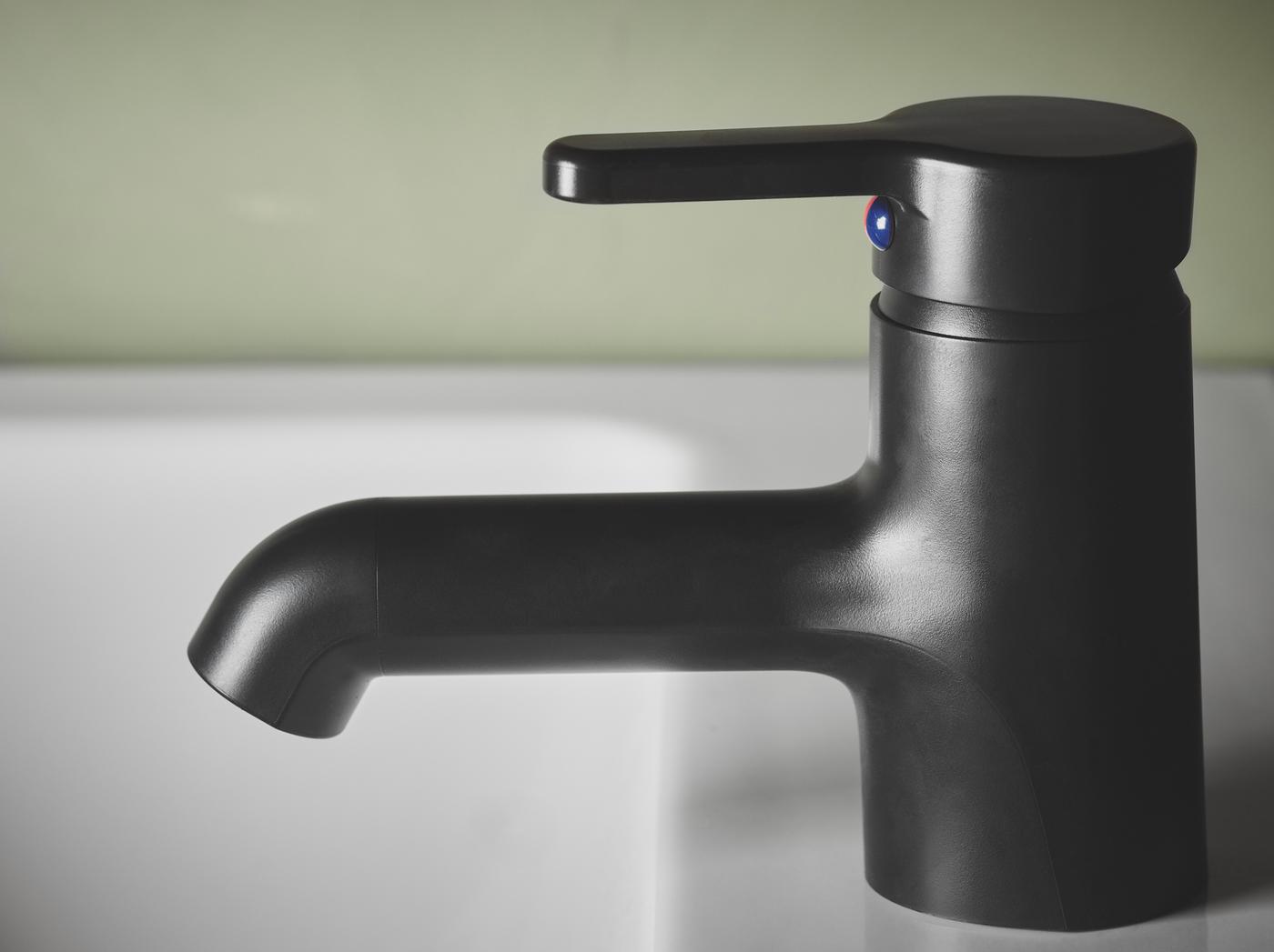 Gambar dekat paip pencampur sink SALJEN buatan reka bentuk anggun plastik hitam, digunakan pada sink putih.