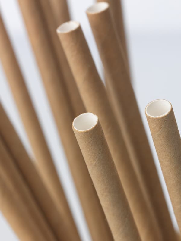 Gambar dekat sebelas straw kertas. Straw berwarna coklat di luar dan putih di dalam.