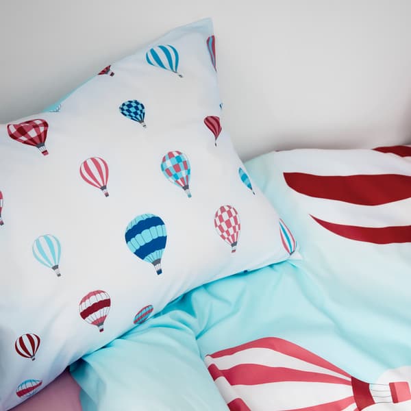 Gambaran dekat sarung kuilt UPPTÅG menunjukkan belon udara panas yang berwarna-warni terbang merentasi sarung bantal dan sarung kuilt.