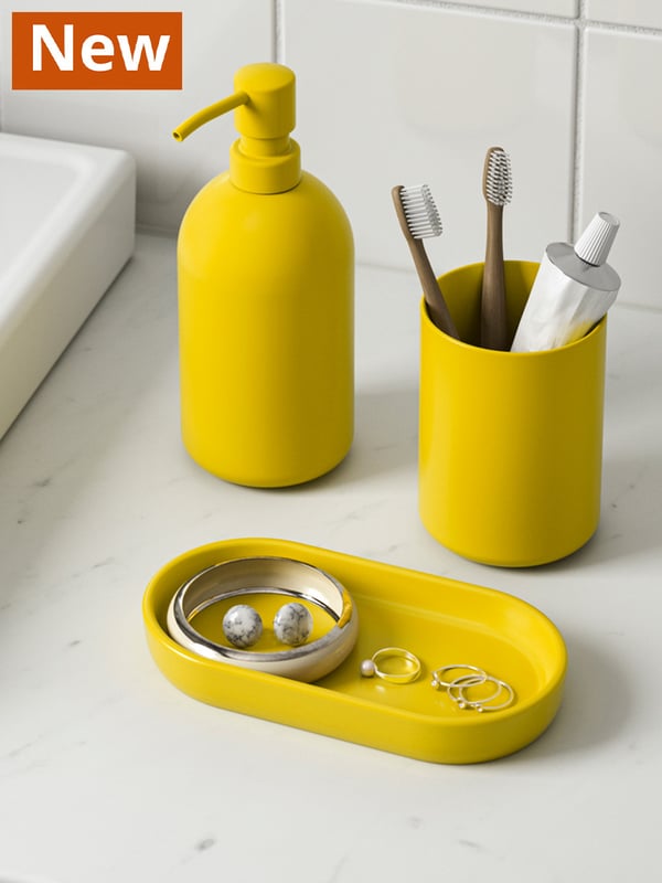 GANSJÖN 3-piece bathroom set in yellow. The cup holder is filled with toothbrushes and toothpastes and some accessories.