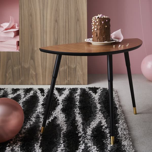Gâteau déposé sur une table d’appoint LÖVBACKEN posée sur un tapis noir et blanc.
