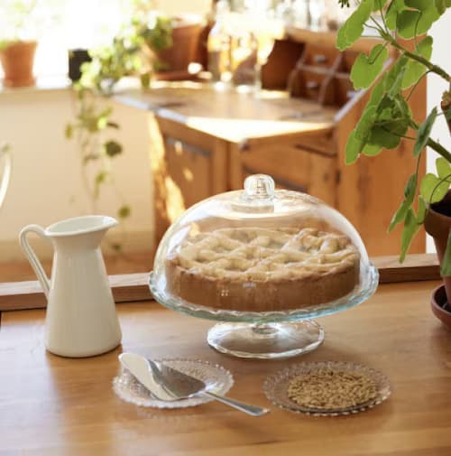 Gateau sous cloche en verre avec une pelle à tarte sur le côté.