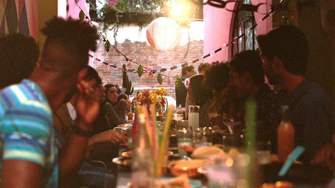 Gathering of people at a long table celebrating together surrounded by tableware and decorations from the ÖMSESIDIG collection 