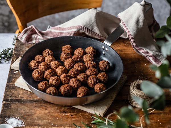 Gebratene HUVUDROLL Proteinbällchen für das Rezept Plantbullar mit Pilz-Maronen-Ragout stehen in einer Pfanne auf einem Brett.