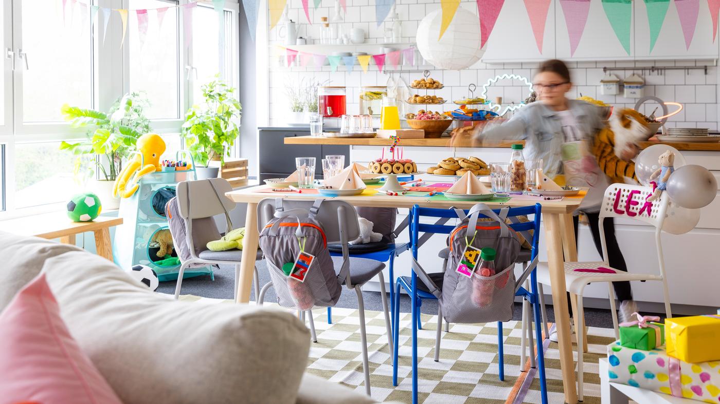 Geburtstagstisch. Ein Mädchen schnappt sich eine Zimtschnecke vom reich gedecktem Tisch. 