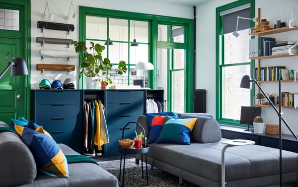 Gedeelde woonruimte met donkergrijze IKEA FLOTTEBO slaapbank en blauwe NORDMELA ladekast.