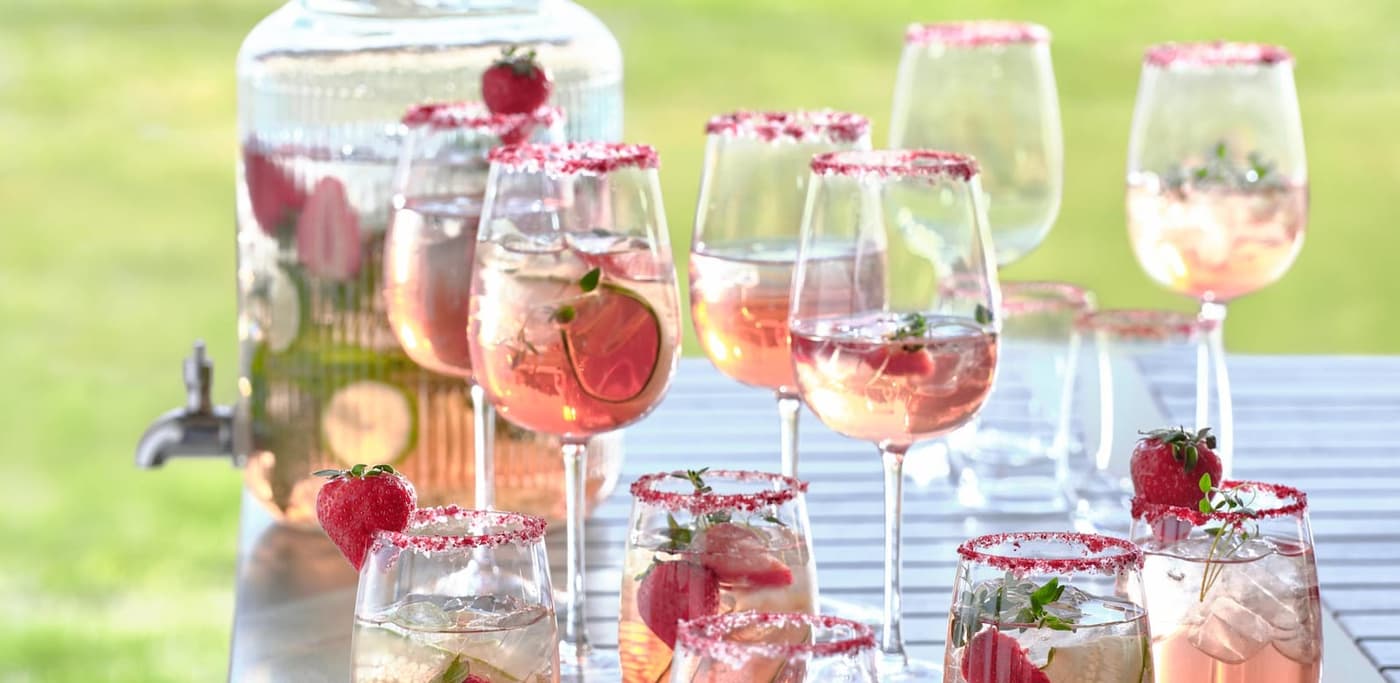 gefüllte Gläser und ein Getränkespender auf einem Tisch im Garten