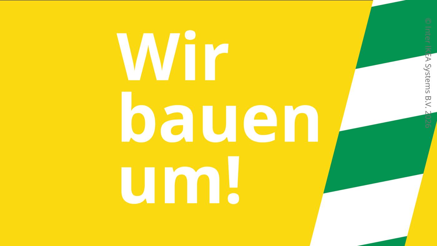 Gelber Hintergrund mit weißer Schrift „Wir bauen um!“ und grün-weißen diagonalen Streifen am Rand.