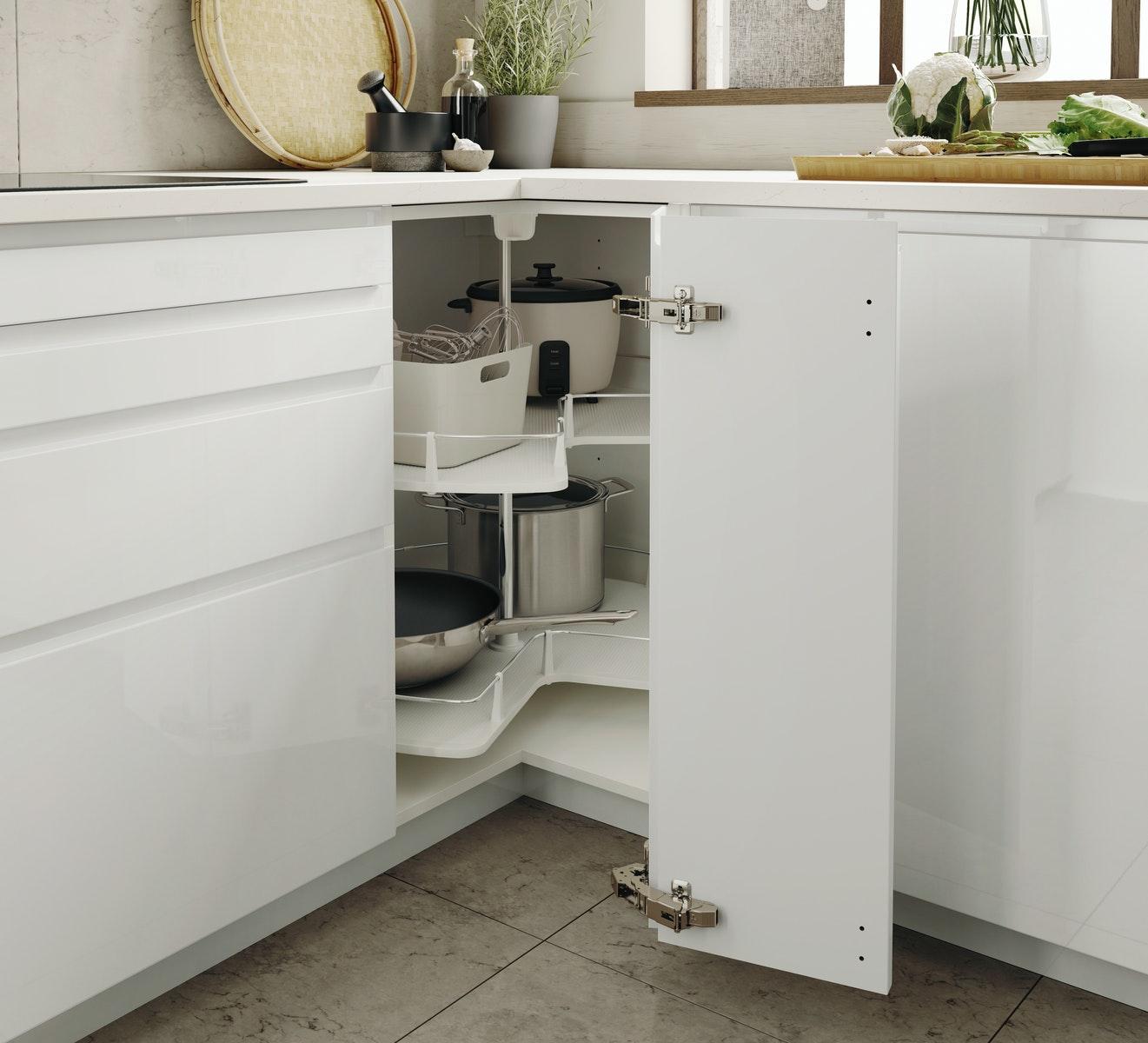 Geöffneter Eckschrank mit hochglanz weißen VOXTORP Fronten unter weiß marmorierter EKBACKEN Arbeitsplatte.