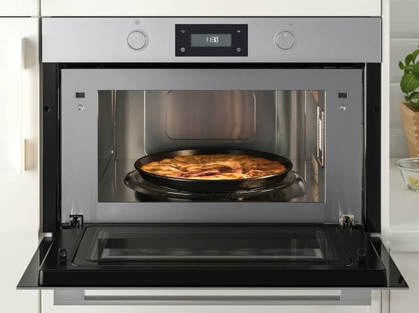Geöffneter Ofen mit Auflauf in einem Blech in der Mitte; oben ist das Bedienfeld mit digitaler Anzeige und zwei Drehknöpfen sichtbar.