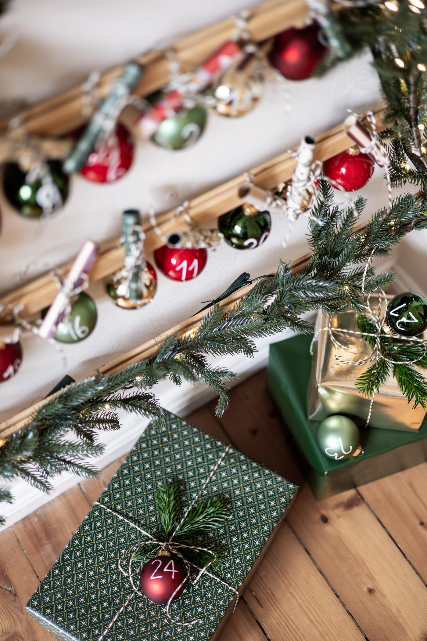Geschenke die unter einer Dekoration auf dem Boden liegen in grünem Geschenkpapier mit weihnachtlicher Deko.
