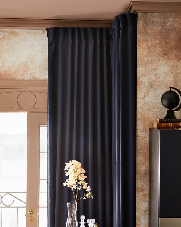 غرفة بستائر معتمة MAJGULL بلون أزرق داكن، مفتوحة لإظهار الضوء، ومجموعة من الزهور في مزهرية زجاجية.