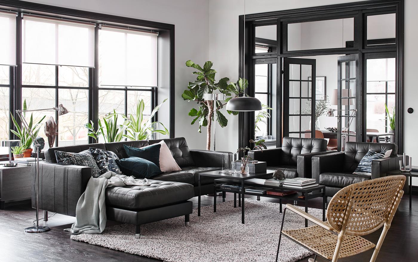 غرفة جلوس أسود، وبيج وأبيض بها كنبة جلد سوداء مع أرائك استرخاء وكرسيين بذراعين متجاورين.