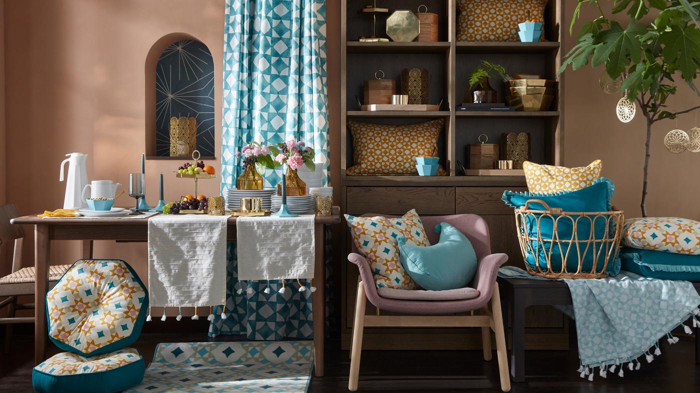 غرفة جلوس مفروشة ومزينة بمجموعة منتجات GOKVÄLLÅ مثل الوسادات والمزهريات والشمعدانات وستارة وسجادة.