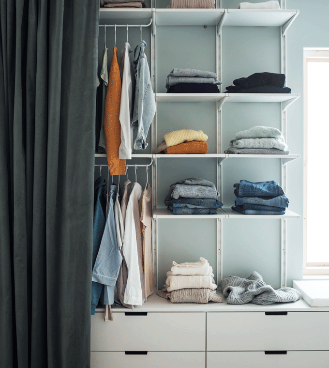 GIF d’un rideau se fermant pour cacher tout un mur de rangements constitués d’étagères ouvertes et de commodes blanches.