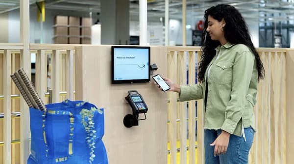 Giovane donna che uso il suo smartphone per il pagamento nelle casse IKEA Shop&Go.