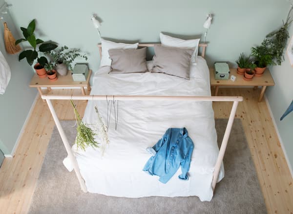 GJÖRA birch bed frame with a low headboard and high footboard with white textiles and ash bedside tables, seen from above.