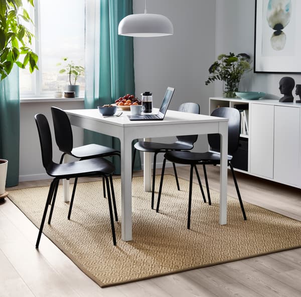 Glad geweven sisal vloerkleed onder een eettafel met een laptop en etenswaren erop.