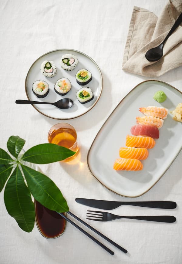 GLADELIG borden en schaaltjes met sushi erop.