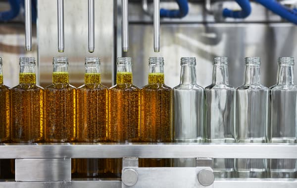 Glass bottles being filled with oil on a production line.