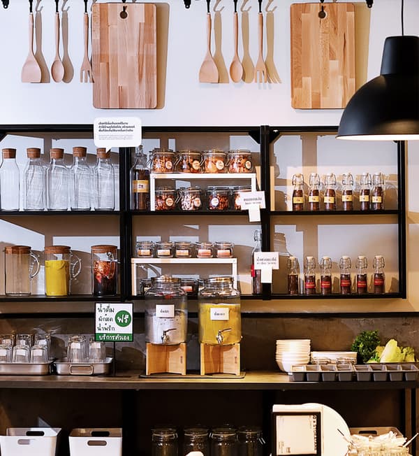 Glass bottles, spatulas and chopping boards are displayed on a shelf and hung on the wall.