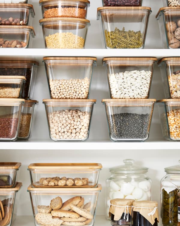 Glass food containers with bamboo lids stacked on top of eachother, all filled with different kind of food