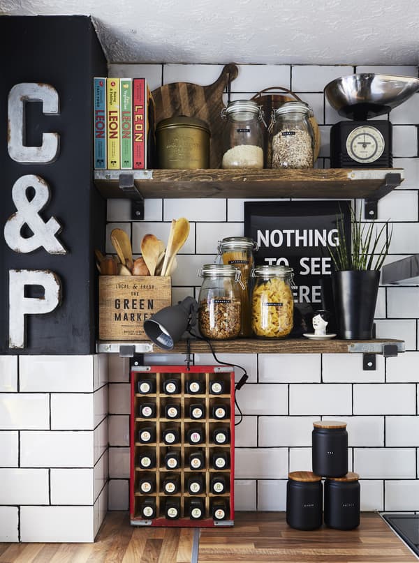 Glass jars with pasta and utensils in an old wooden box displayed on open shelves made from old restored scaffold board.