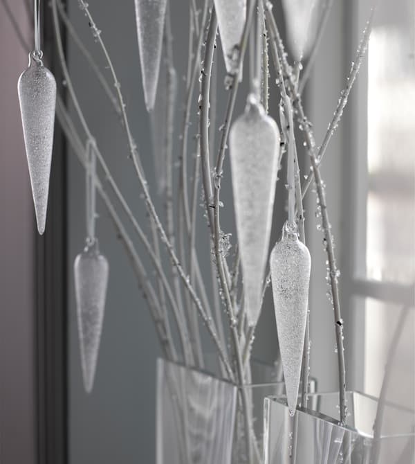Glass ornaments hang from twigs in a window.