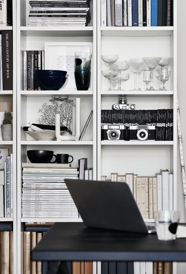 Glassware and books in an open storage unit.