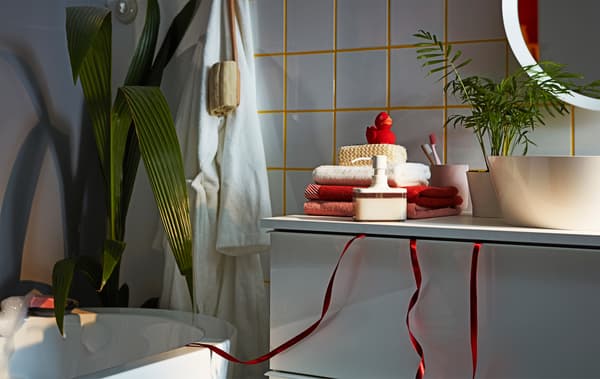 ภายในห้องน้ำเน้นไปที่อ่างล้างหน้า GODMORGON/กูดมอร์รอน พร้อมกับริบบิ้นของขวัญแขวนลงมาจากลิ้นชักชั้นบนที่ปิดไว้