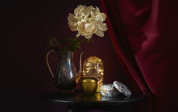 Gold accessories and lighting on a round table against a dark red backdrop.