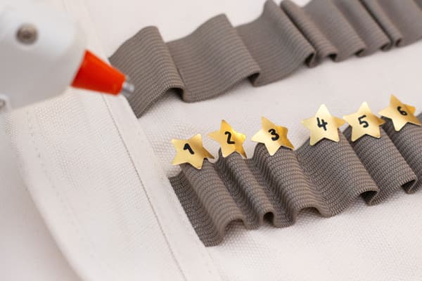 Goldsterne mit Zahlen werden auf das Gummi des Mäppchens geklebt.