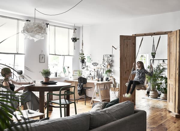 Grand coin séjour avec bureau, canapé, table et Hania sur la balançoire dans le passage de porte.