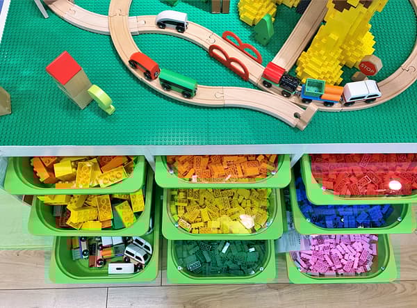 Grands bacs verts contenant des blocs de construction et insérés dans un module de rangement.