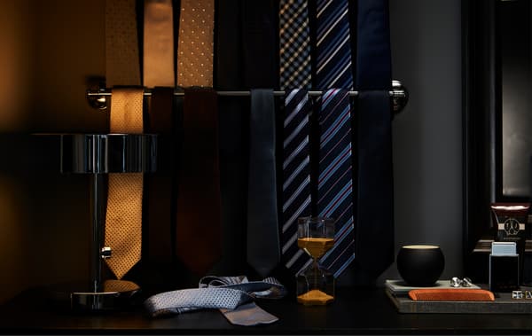 Gravatas en marrón dourado, azul, negro, gris e raias colgadas nun toalleiro cromado IKEA para facilitar a visión.