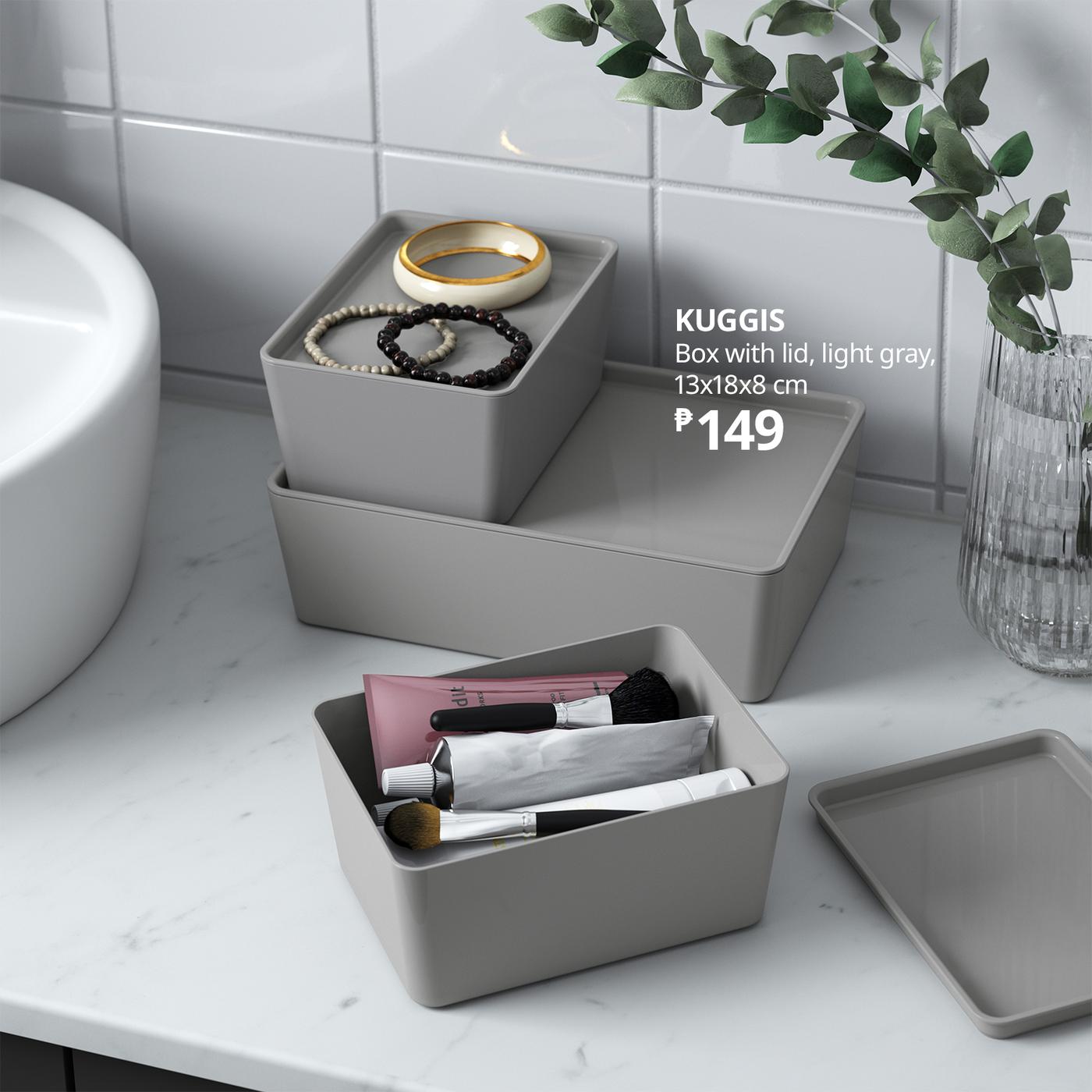 Gray KUGGIS storage boxes on a marble bathroom counter hold jewelry and makeup brushes, with a glass vase of greenery nearby; a clean, calm product display shows the 149-peso price.