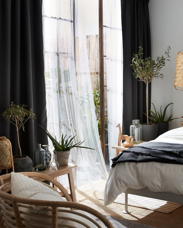Gray room darkening curtains combined with sheer white curtains, a BUSKBO armchair and olive trees in pots.