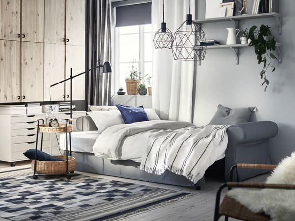 Gray VRETSTORP sofa with a lamp and LUBBAN rattan trolley table with storage on the side.
