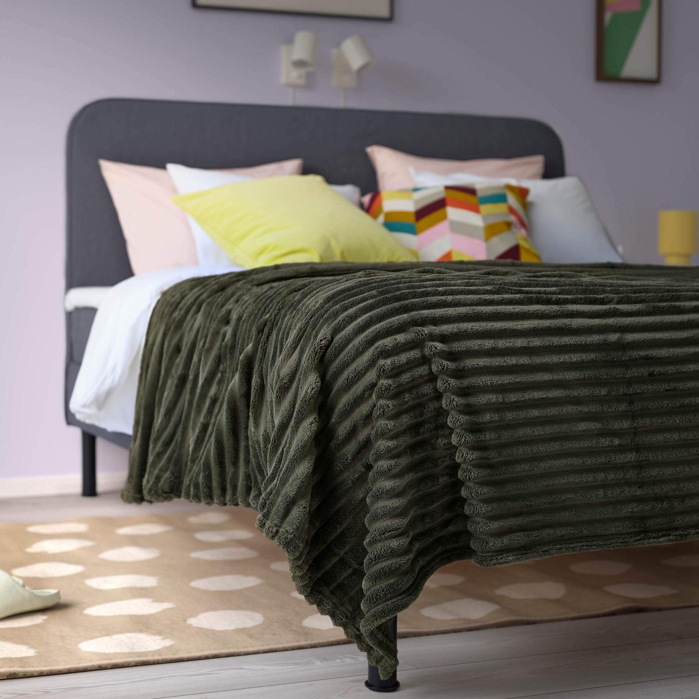 Green GULLSTRÅLE blanket on bed.