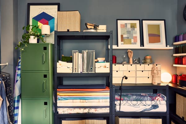 Green storage cabinet next to blue shelving packed with magazine files and swatches of IKEA fabrics by the metre.