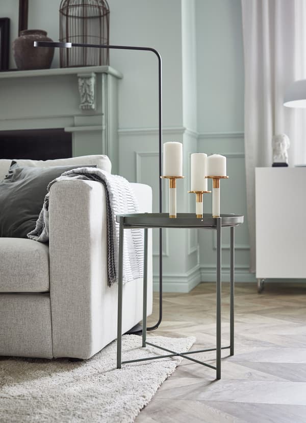 Grey coffee table with three candle holders on top.