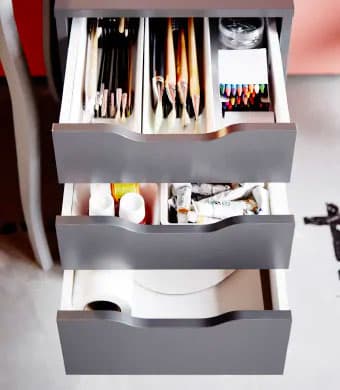 Grey drawer unit with the three drawers open and filled with art supplies