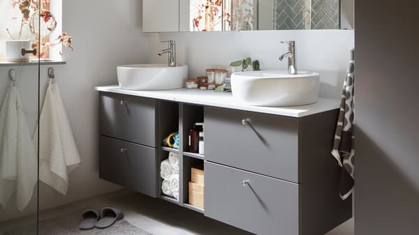 Grey GODMORGON/TOLKEN bathroom furniture with four drawers for hidden storage and four compartments for open storage.