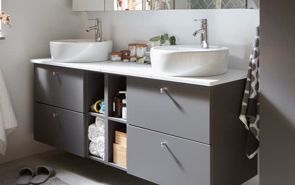 Grey GODMORGON/TOLKEN bathroom furniture with four drawers for hidden storage and four compartments for open storage.