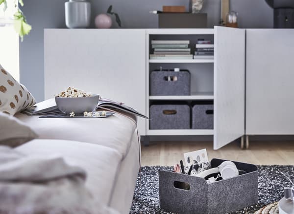 Grey storage boxes inside a low white storage unit.