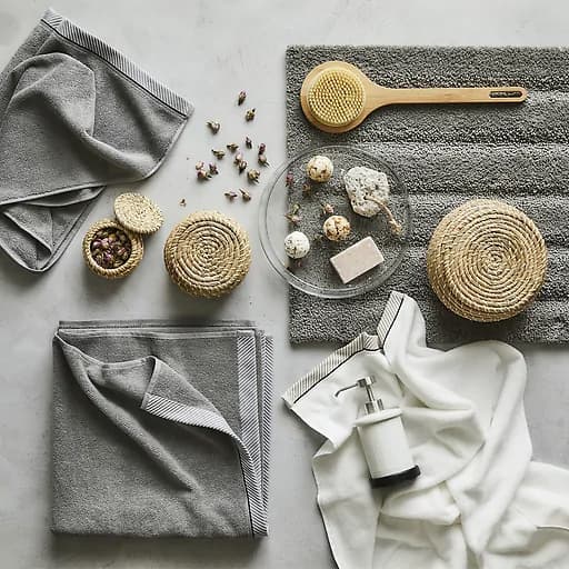 Grey towels and bathroom accessories laid out on a grey surface.